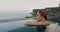 Woman with flower in the hair enjoying sea view on the edge of swimming pool. relaxing vacation