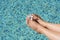 Woman with flower holding feet over water in swimming pool, closeup. Space for text