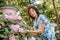 Woman with a flower. Senior Hispanic Woman Working In Garden. Close-up portrait of an older woman on walk with flowers.