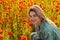 Woman on flowering poppy field. Summer holidays on nature. Girl on poppies meadow with poppys flowers. Summer.