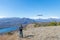 Woman flying drone outdoors with remote control. One person in scenic landscape driving drone filming photographing snowcapped mou