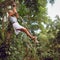 Woman flying high on rope swing on wild jungle background