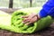 A woman folds and packs a sleeping bag, going on a journey through the forest. The concept of tourism and ecotourism. Equipment fo