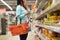 Woman with food basket at grocery or supermarket