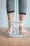 Woman foot standing on electronic weigh scales with tape measure leg winded