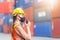 Woman Foreman in hardhat and safety vest holding holding clipboard checklist and talks on two-way radio control loading containers