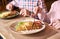 Woman with fork and knife during lunch. Focus on crepe sandwich served with vegetables and cheese. Blurred background.