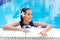 woman with frangipani flower in hair, relaxing in the pool in full blue dress