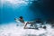 Woman freediver swim underwater over sandy bottom with sand