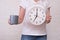 Woman freelancer with clock showing 7 am and a cup of coffee, punctuality during remote and distant work concept