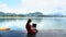 Woman Freelancer Sitting on Wooden Pier at Lake and Working on Project at Laptop