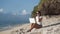 Woman freelancer in sunglasses works on beach with laptop and talks on phone