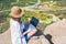 Woman freelancer in tourist clothes and straw hat with a laptop on top of a mountain