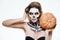 Woman with frightened skeleton makeup holding pumpkin