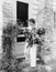 Woman in front of her house gathering flowers in her arms