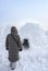 A woman in front of an igloo, a traditional shelter of the northern peoples from the cold, made of snow bricks