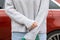 woman in front of lateral door red car in warm pullover blue jeans