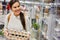 Woman in front of a refrigerated display case carries a stack of egg cartons