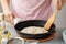 Woman frying mexican flatbread on cast iron pan.