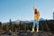 Woman in full height smile with teeth happiness hiker in yellow raincoat jumping up with his hands up on the mountain