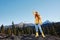 Woman in full height smile with teeth happiness hiker in yellow raincoat jumping up with his hands up on the mountain