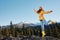 Woman in full height smile with teeth happiness hiker in yellow raincoat jumps up on the mountain trip in the fall and