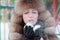 Woman in fur hat blowing snowflakes in winter