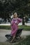 A woman in a futuristic pink raincoat in the park.