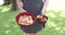 Woman in the garden carrying in her hands two bowls with plums