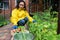 Woman gardener agriculturist picking organic vegetables and putting them in a wooden box for sale at a farmers market