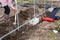 Woman gardener building  base of the greenhouse outdoors in spring.