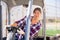 Woman gardener driving agricultural vehicle in hothouse