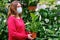 Woman gardener in face mask buys spathiphyllum houseplants for her flower garden. The sales of potted plants for a hobby during