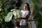 Woman gardener holding caladium houseplant with large white leaves in clay pot