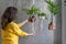 Woman gardener holding macrame plant hanger with houseplant over grey wall. Hobby, love of plants, home decoration