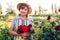 Woman gardener picks bouquet of red dahlias and zinnias in summer garden. Senior flower farmer enjoying blooms at sunset