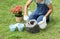 Woman gardener pouring soil in pot for glowing plants - Cultivation and caring for outdoor potted plants.