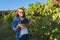 Woman gardener walking with basket with grape harvest, vineyard background