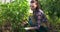 Woman gardener is working in greenhouse weeds and loosens ground with a shovel.