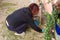 Woman gardening in the garden by planting aloe vera plants next to plastic pipes as a meaning that nature wins over plastic