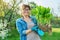 Woman in gardening gloves holding bush of hosta plant with roots for dividing planting