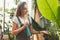 Woman gardening and profession concept -gardener with sprayer in greenhouse