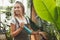 Woman gardening and profession concept -gardener with sprayer in greenhouse