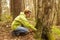 A woman geocaching. Women in woods find geocache container.