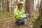 A woman geocaching. Women in woods find geocache container.