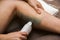 Woman getting legs waxed for hair removal in home