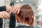 Woman getting a new haircut. Female hairstylist cutting hair with scissors in hair salon. Hairdresser hold in hand between fingers