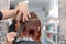Woman getting a new haircut. Female hairstylist cutting hair with scissors in hair salon. Hairdresser hold in hand between fingers