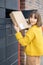 Woman getting parcel from cell of automatic post terminal outdoors