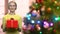Woman with gift box on blurred Christmas background.